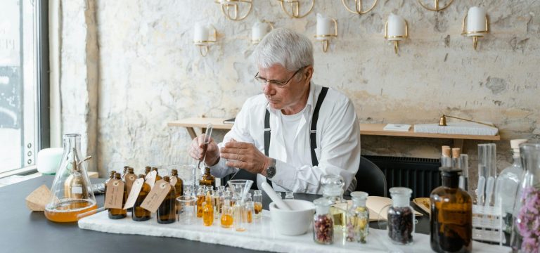 Mann bei der Parfumherstellung – er mischt verschiedene Duftessenzen in einem Laborfläschchen zur Kreation eines individuellen Parfums.