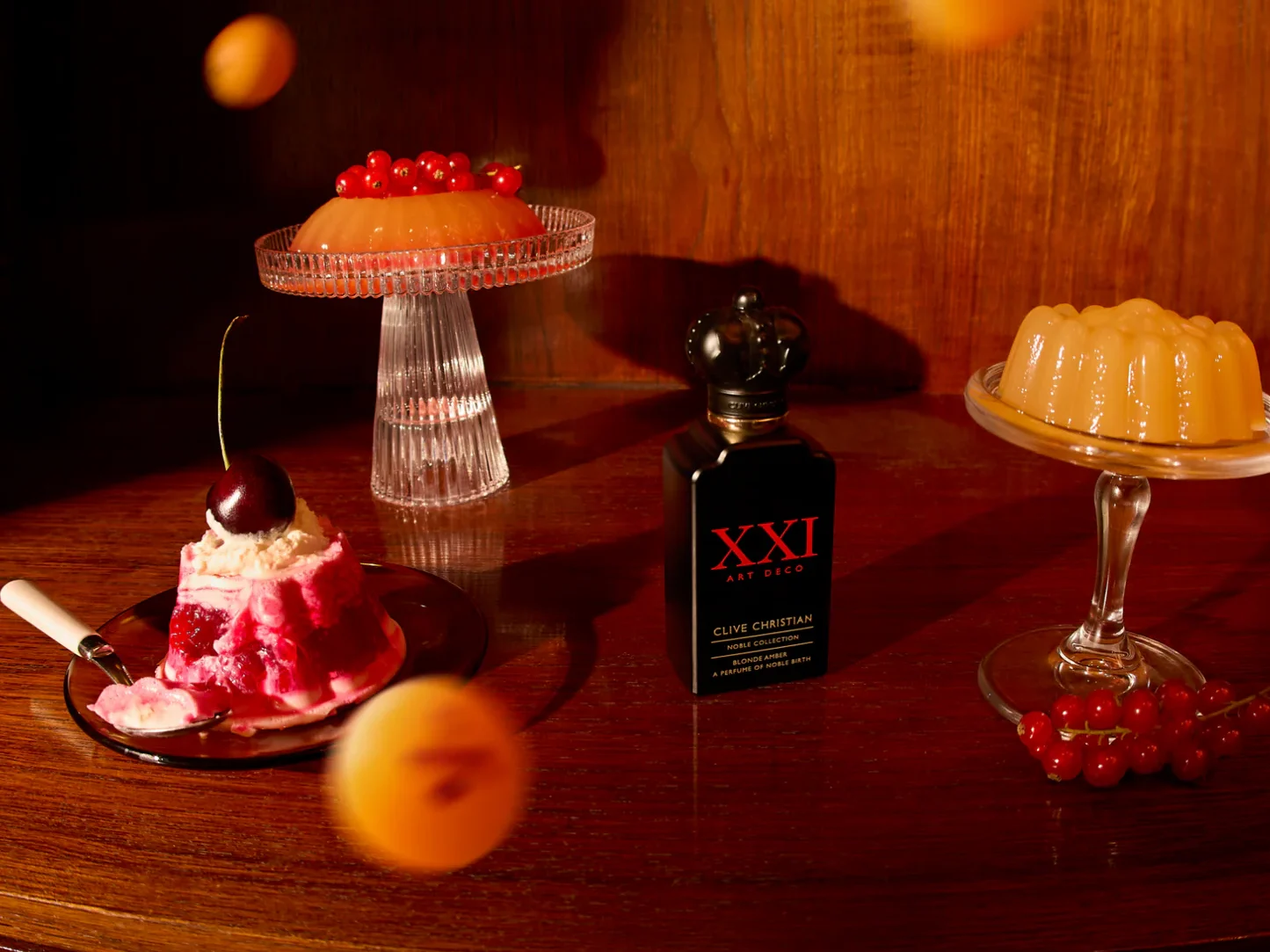 Clive Christian Blonde Amber Parfumflakon neben Kirschkuchen und Orangen-Konfitür – luxuriöses Herbstparfum mit gourmandiger Note
