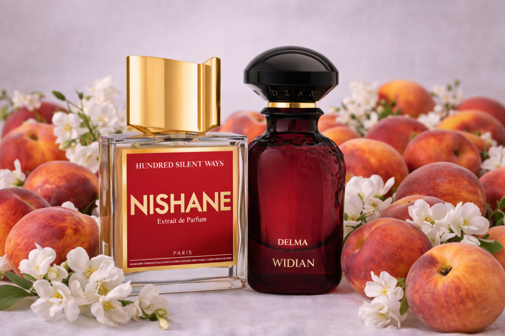 Nishane Hundred Silent Ways und Widian Delma Parfumflakons, umgeben von reifen Pfirsichen und weißen Blüten in einer hellen, eleganten Komposition.